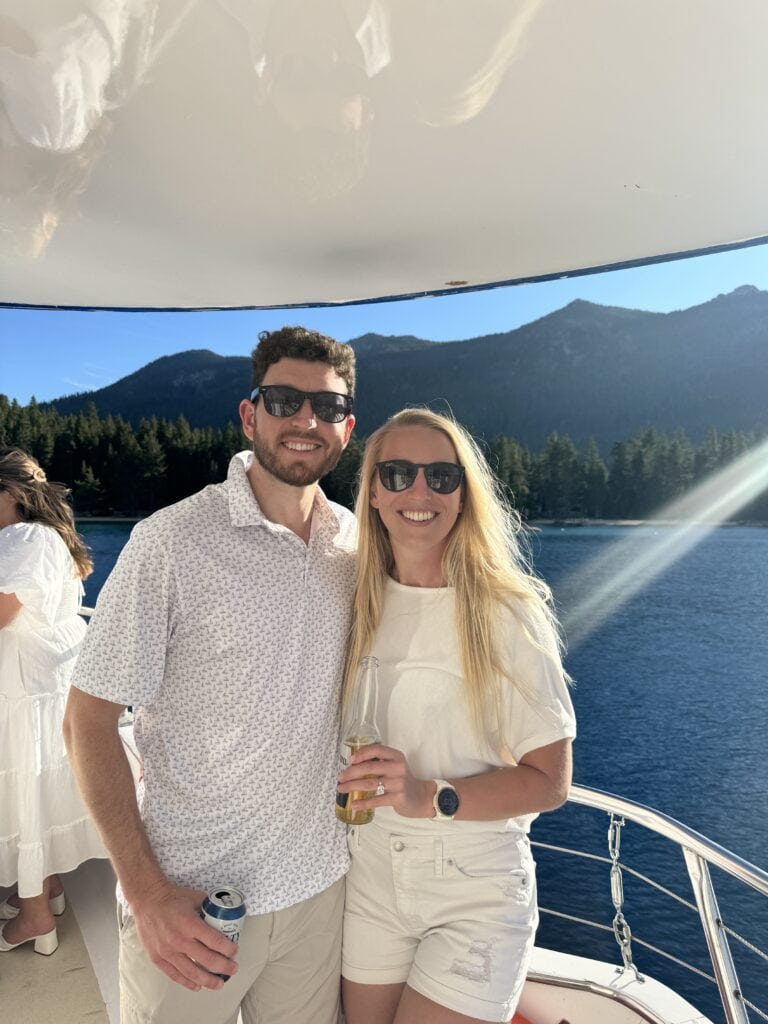 a couple smiles at the camera on a boat on lake tahoe