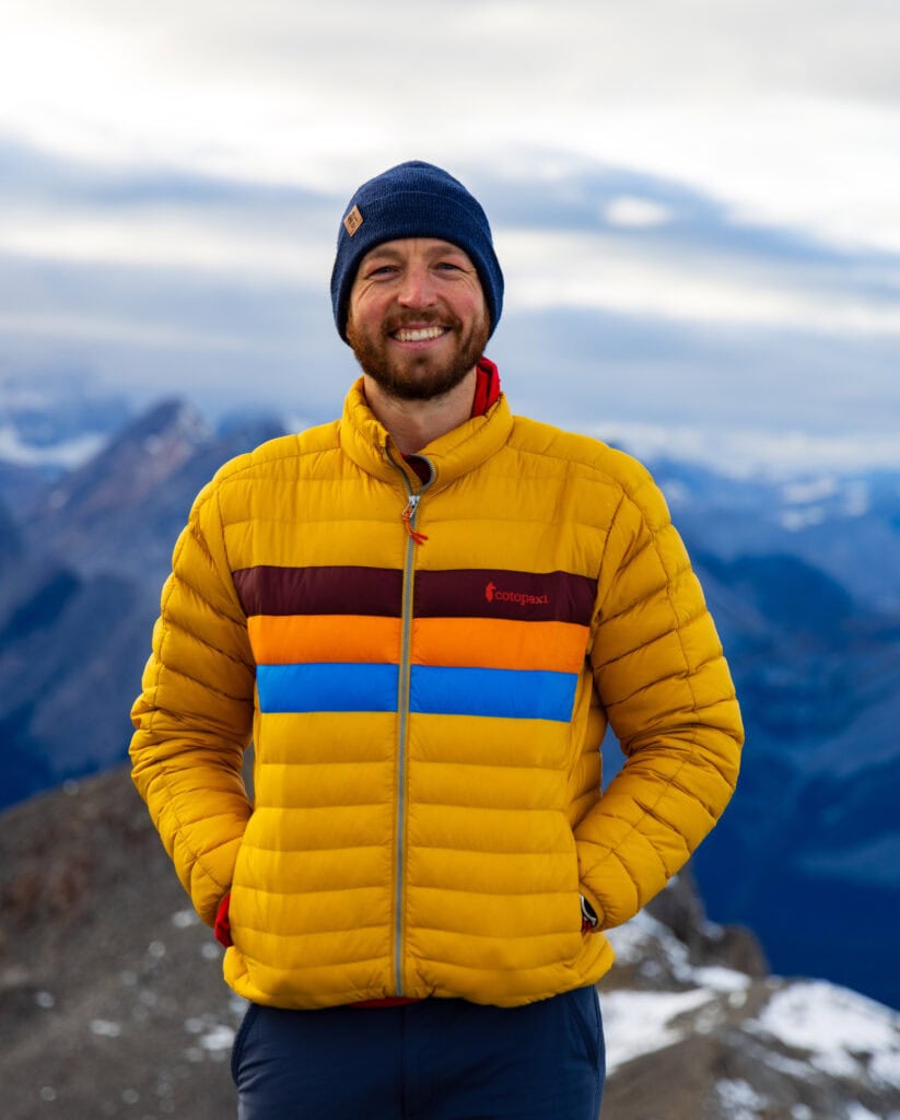 the author in a yellow jacket smiles at the camera