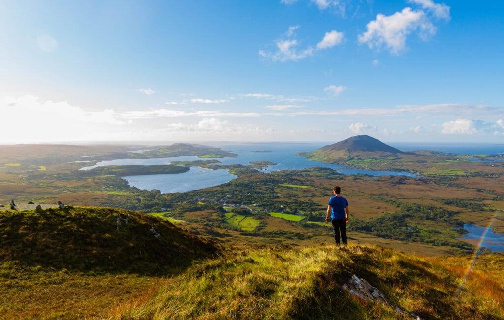 a hiker in a blue shirt looks at the view from the diamond hill hike in connemara national park