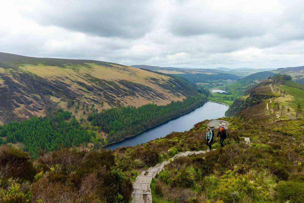 two hikers hike in the wicklow mountains above a lake