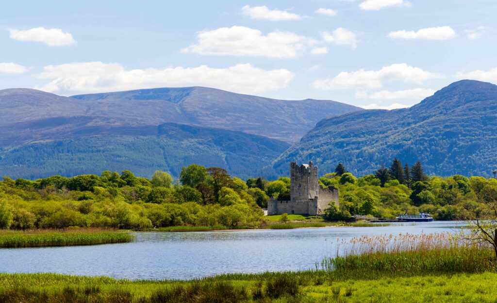 a far off view of the ross castle with the lake in front