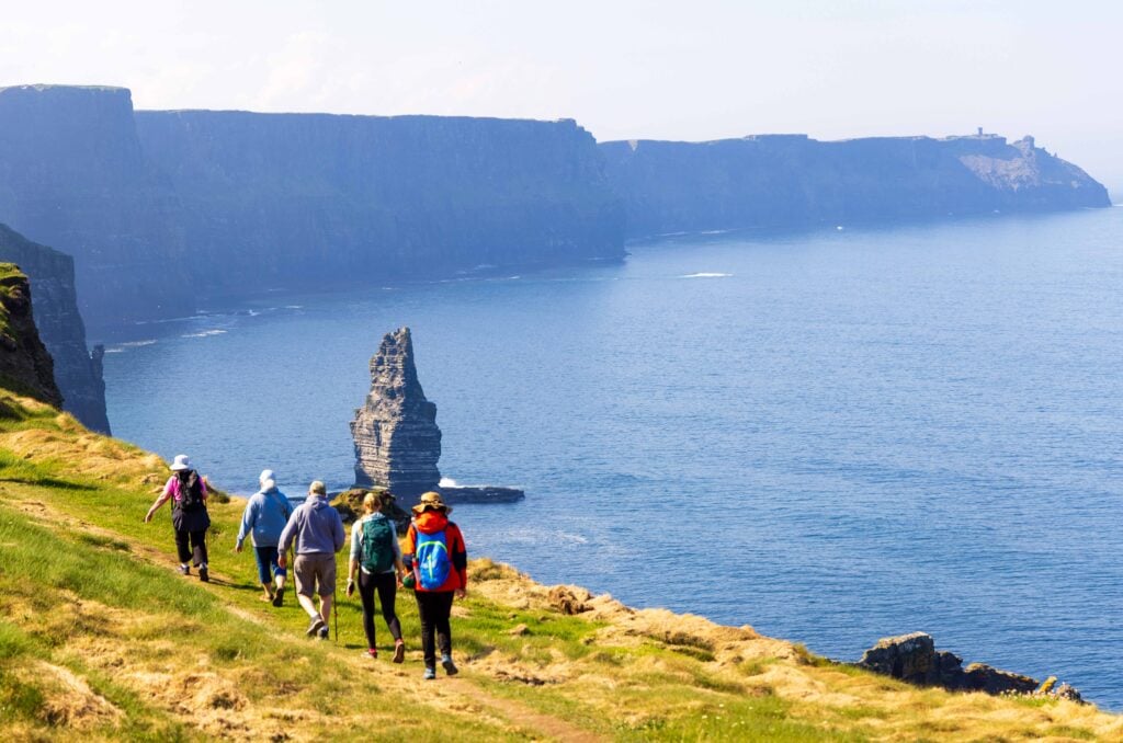hikers walk along the cliffs of moher in ireland