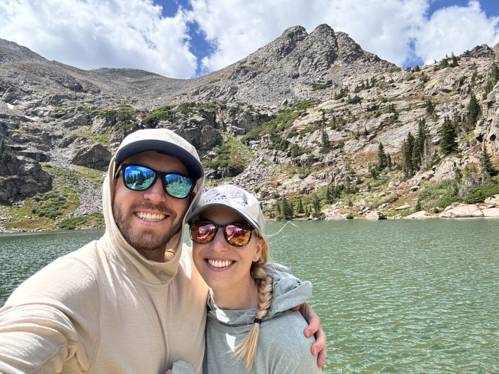 two hikers smile at the camera at fancy lake