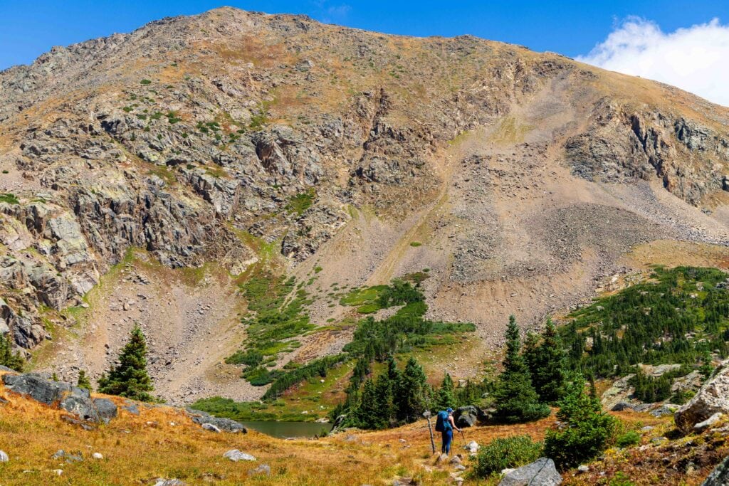 a female hiker walks on the trail with a large mountain in front of her