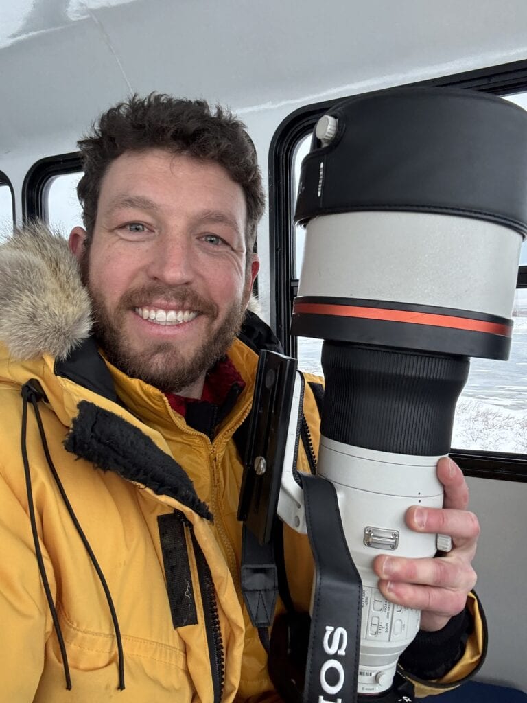 a male holds a camera lens on a polar bear trip