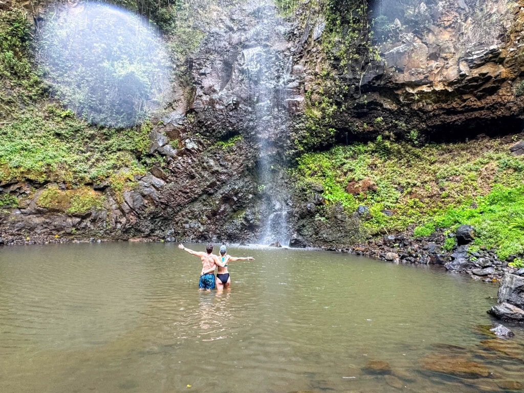 two guests look up at the waterfall after hiking