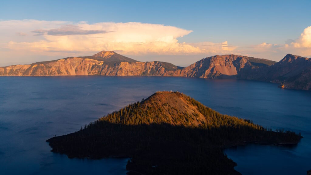 the sun illuminating wizard island as it begins to set