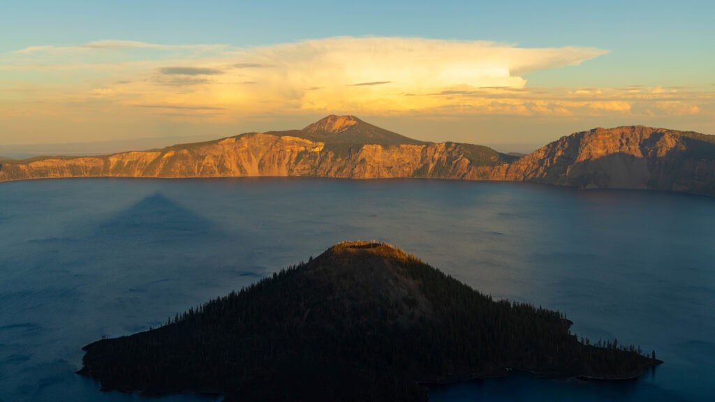 sunset at crater lake with the very tip of wizard island illuminated