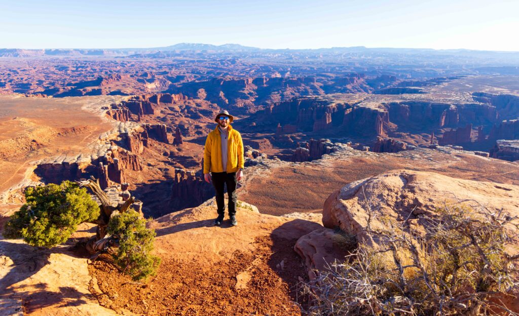 a hiker stands near the edge smiling at the camera
