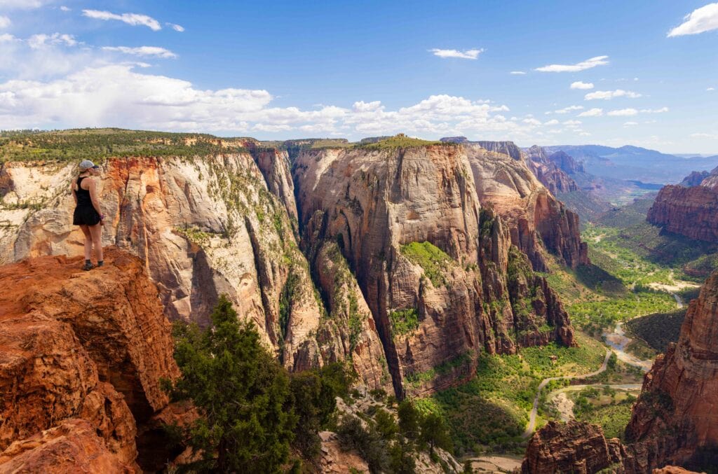 a woman stands at observation point looking out at zion canyon