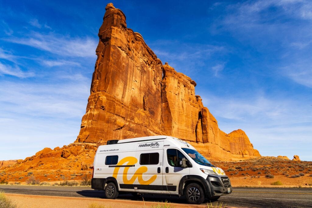 a roadsurfer camper van parked in front of courthouse towers in arches