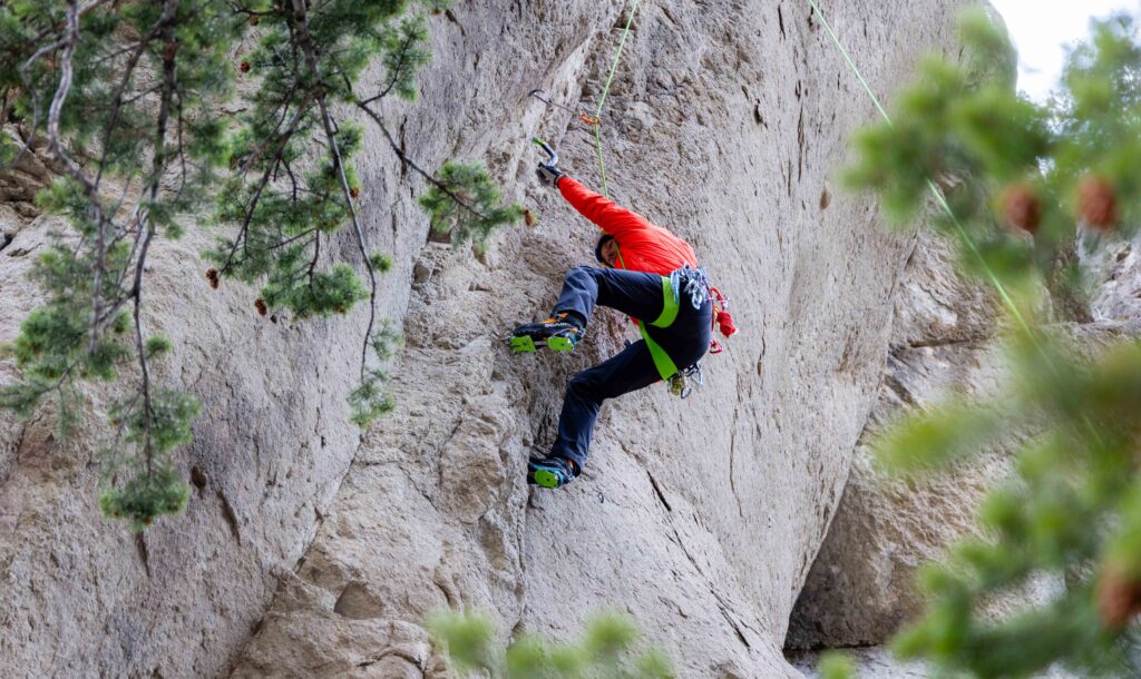 a climber dry tooling high on a rock wall