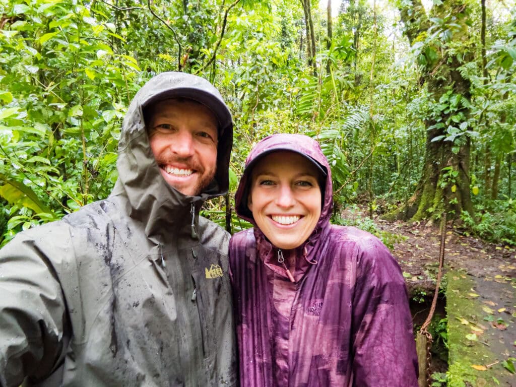 two hikers in rain gear smile at the camera in costa rica