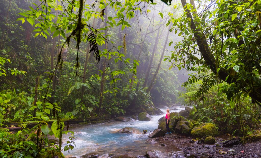a woman looks out at a river in blue falls hike in costa rica