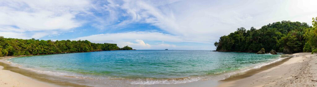 playa manuel antonio with blue water and green trees surrounding it