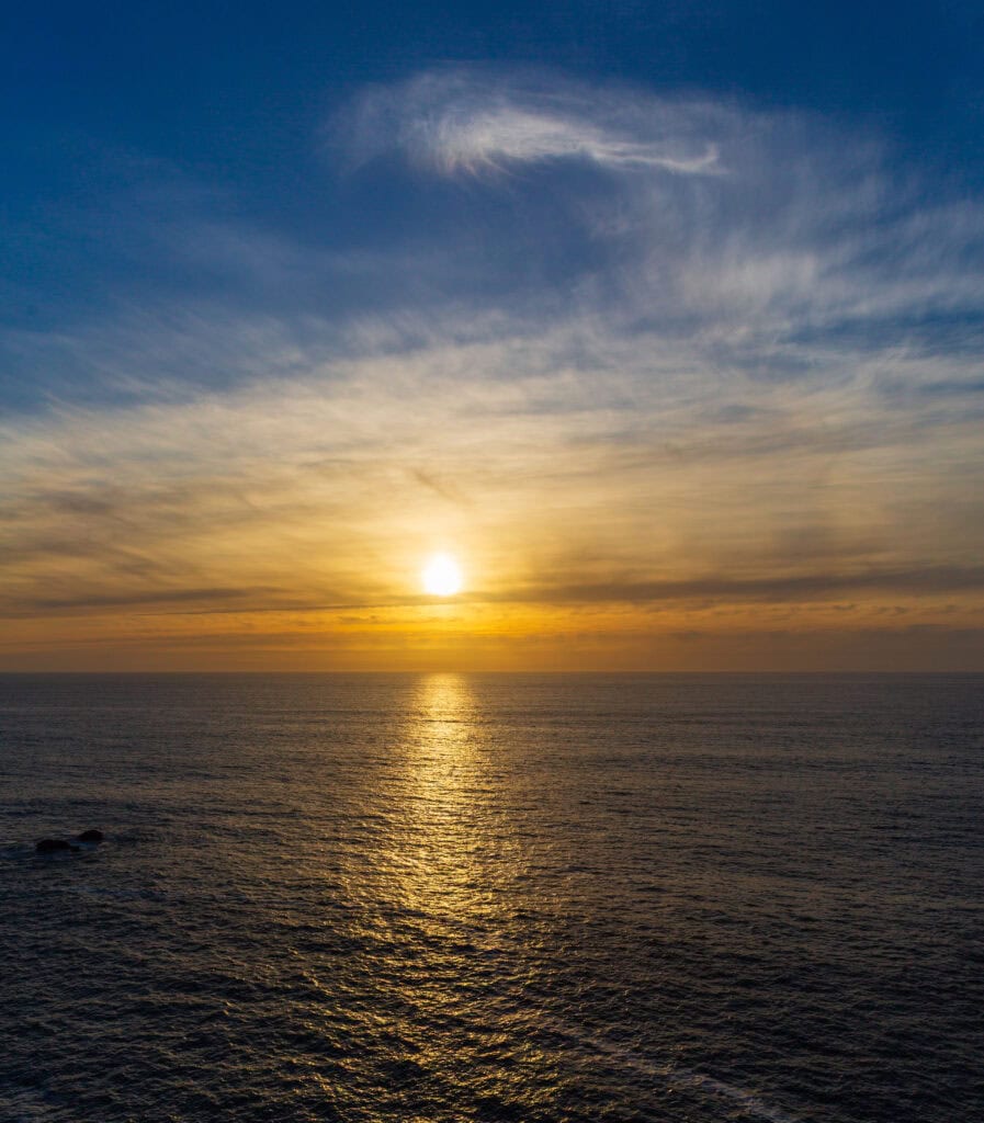 the sun begins to set over the ocean leaving a sun line on the water