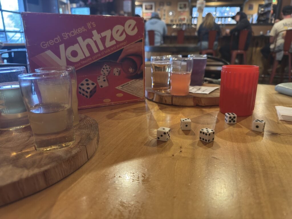 yahtzee dice and the box with small beer glasses also on the table