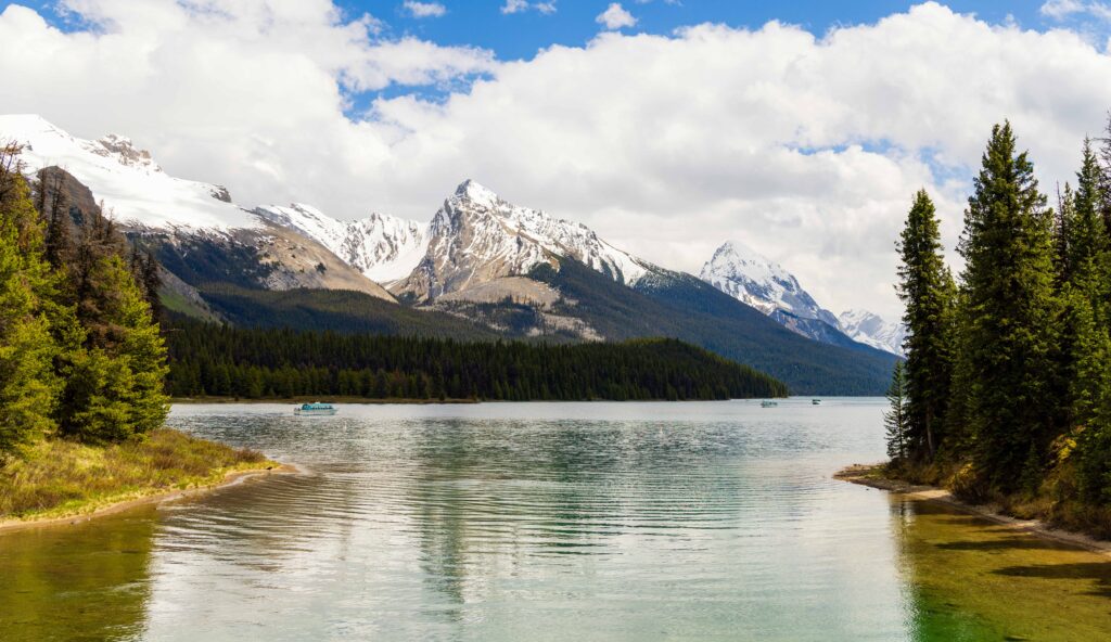 maligne lake in jasper national park with mountains in the background the trees along the side of the frame