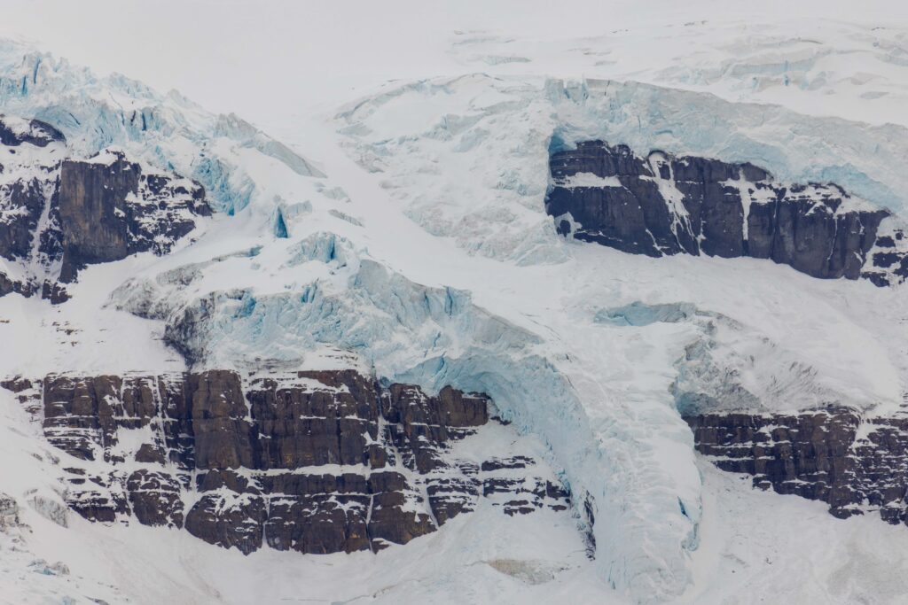 a massive glacier hanging onto the side of a mountain in jasper national park