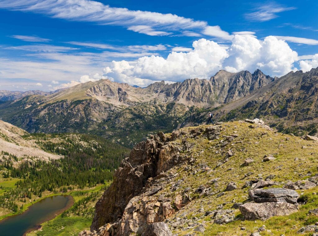 a hiker on a ridge line near arapaho pass with caribou lake below