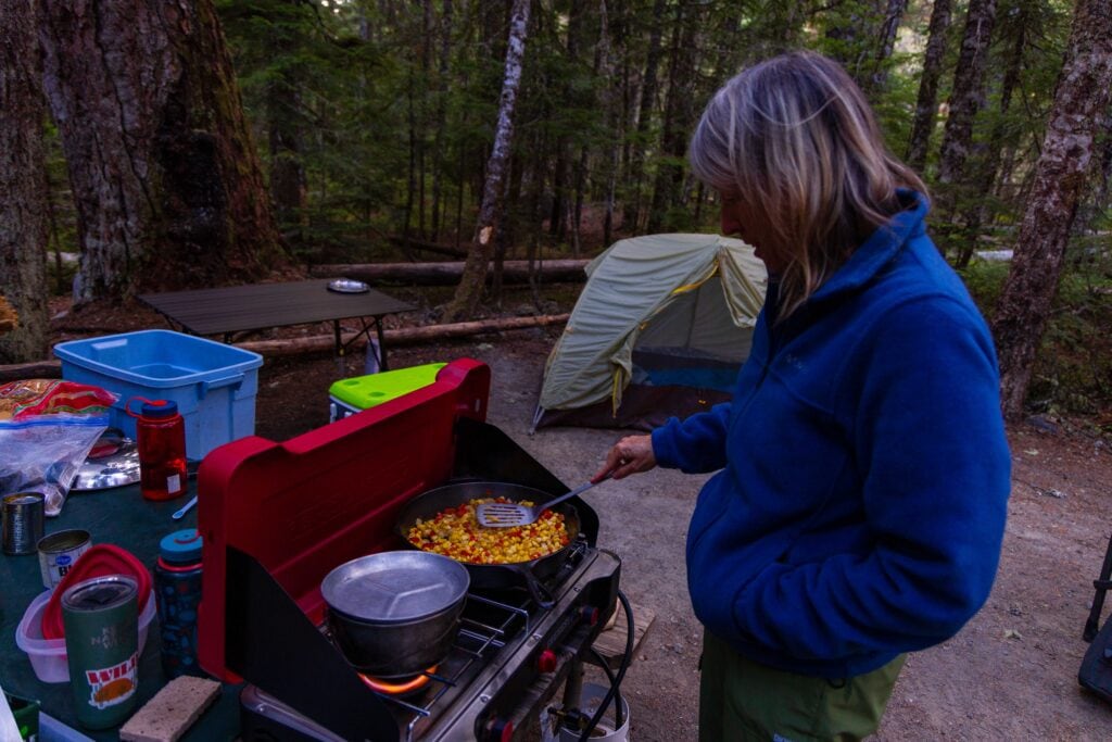 A woman makes food on a camp stove in washington's mount rainier national park