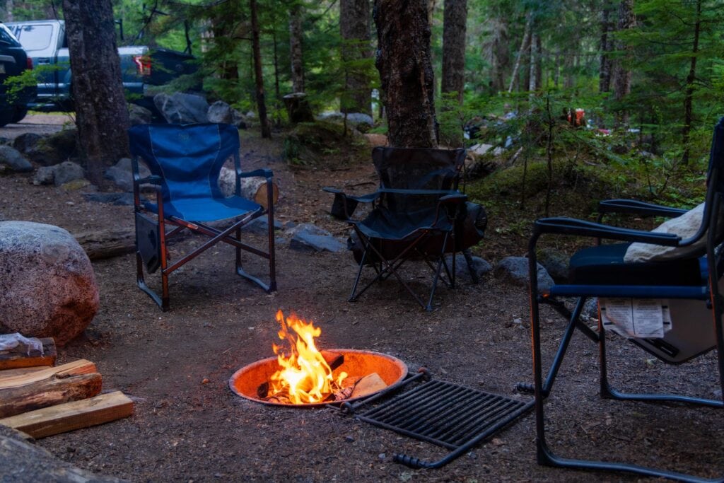 a campfire with chairs around it in a campground