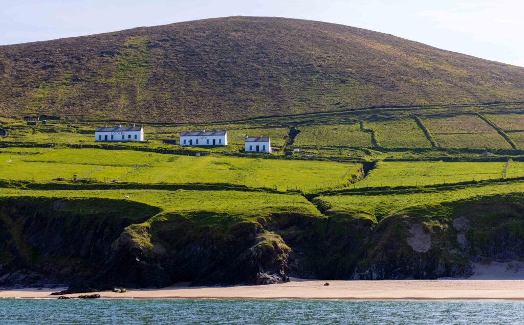house on a green cliff above a beach in ireland