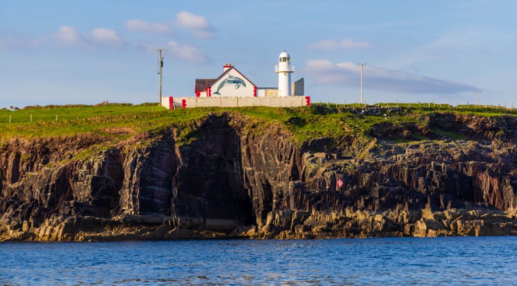 a wgute house and lighthouse on the edge of the cliffs near dingle ireland