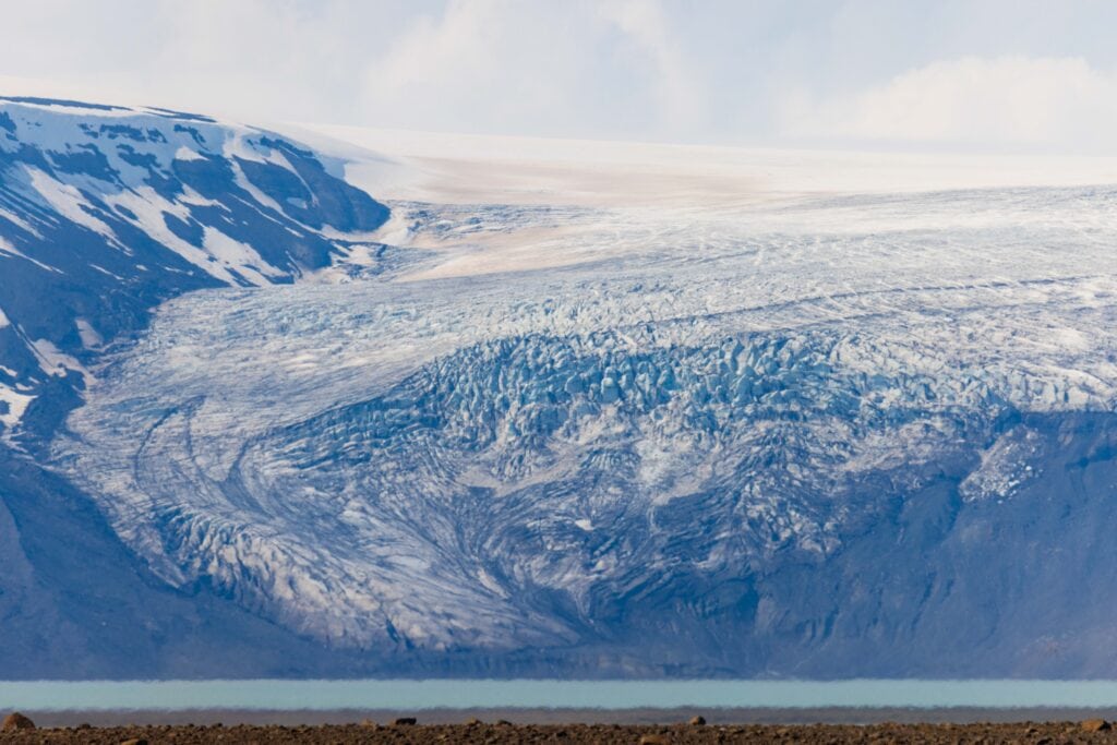 a glacier winding towards a turqoise river as seen along the f35 road