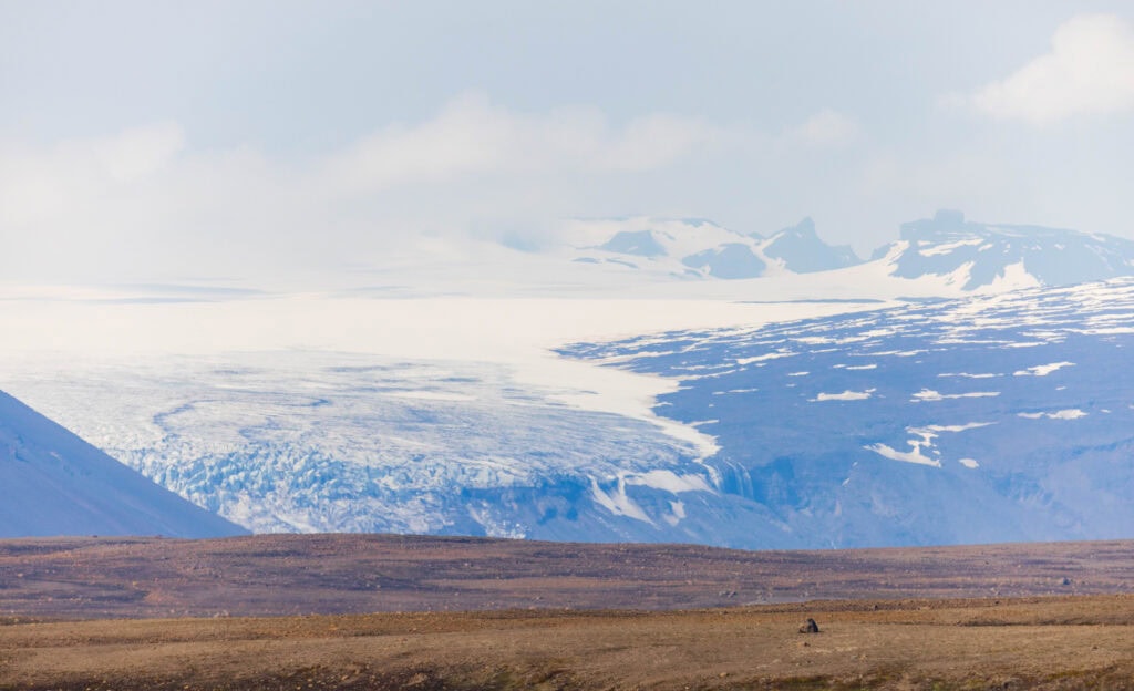 a glacier above a brown hill in iceland