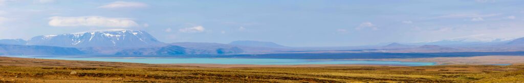a long panorama photo of a very blue lake in iceland