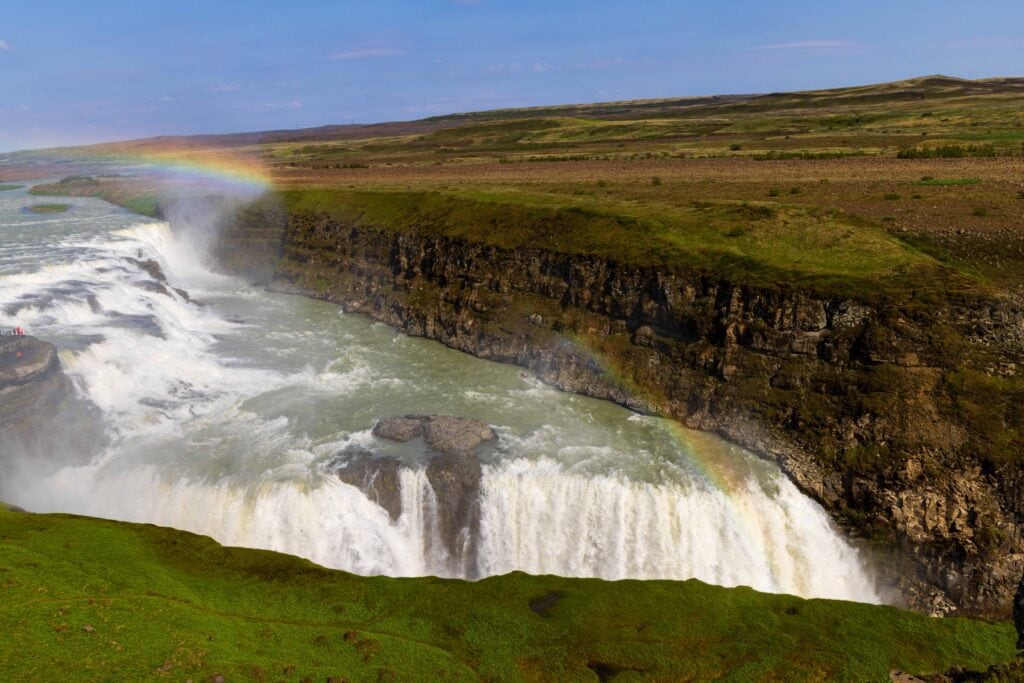 gulfoss waterfall rushing with partial rainbows forming in the mist