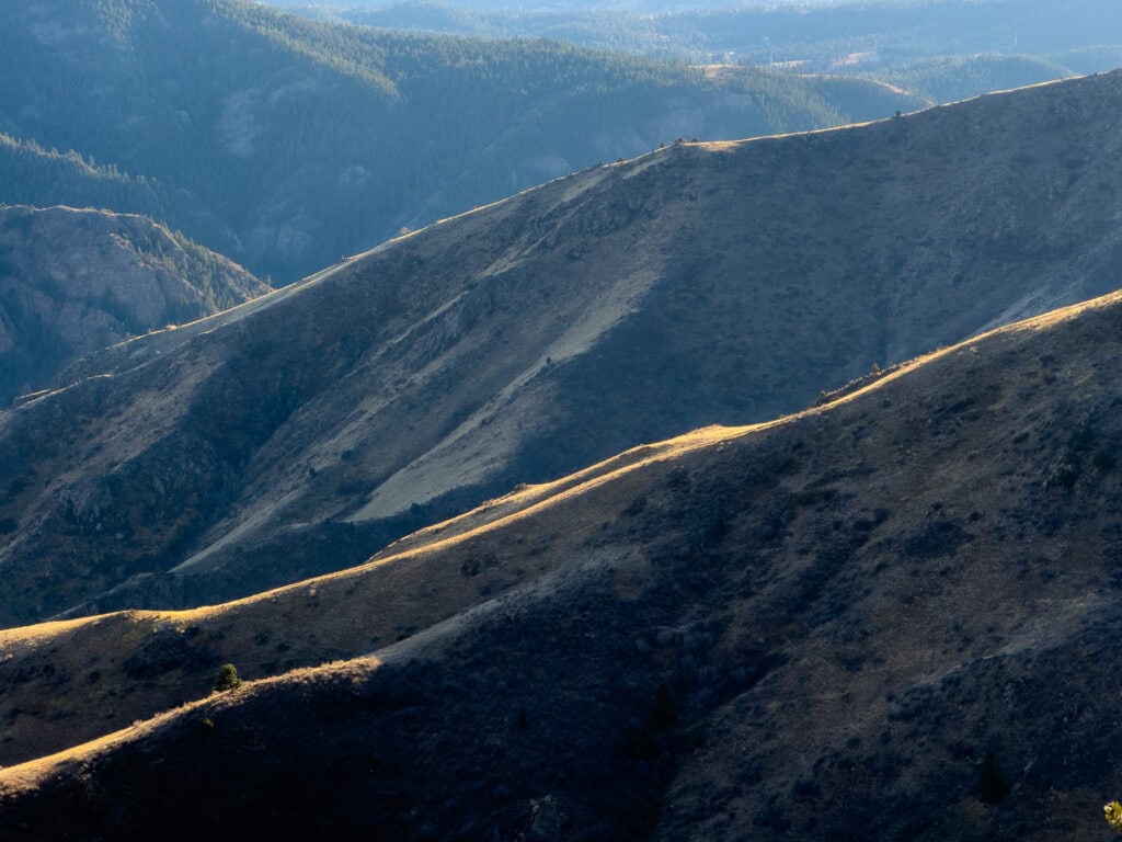 Sweeping view of brown rolling hillsides with dramatic light and shadow