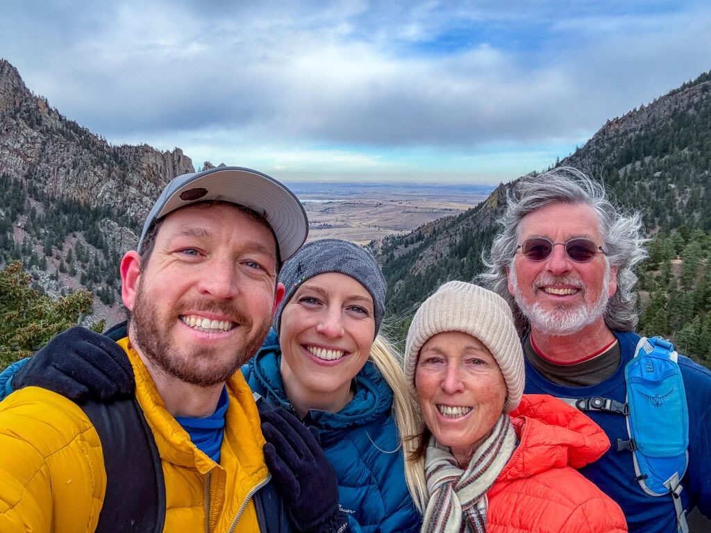 Group selfie of four smiling hikers in winter gear on a trail