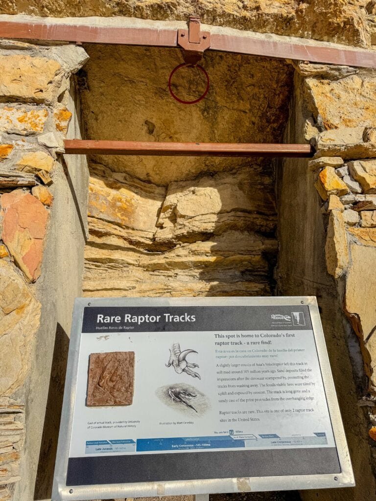 Interpretive sign at a dinosaur nature site with rocky terrain in the background