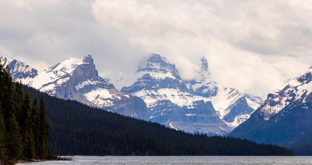 towering snowcapped mountains in jasper national park above maligne lake