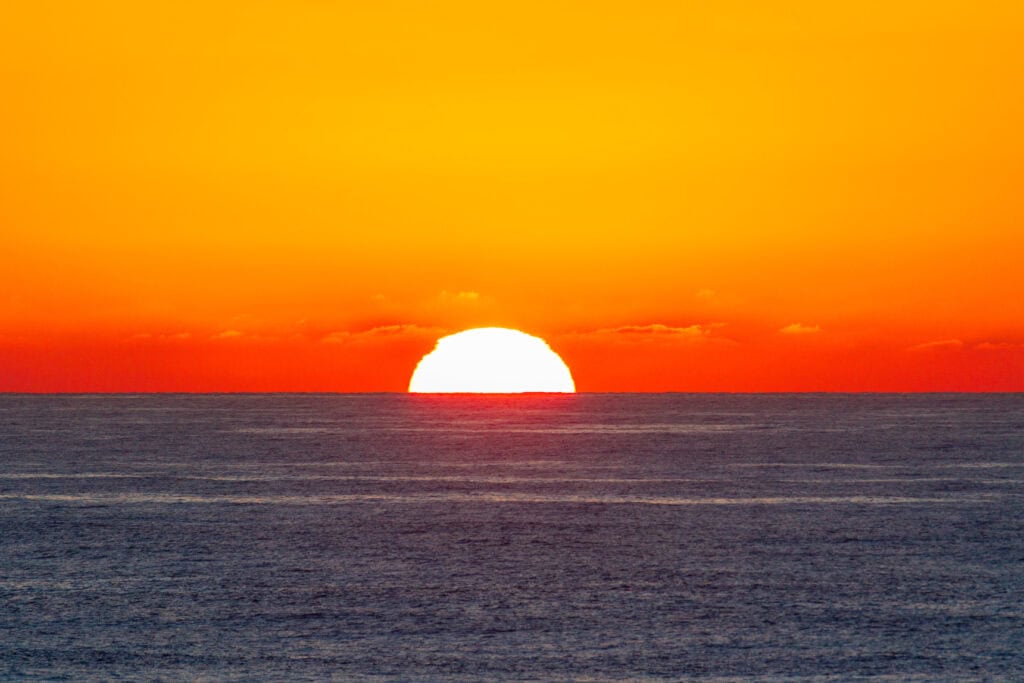 Blazing orange and red sunset casting golden light over the open Pacific