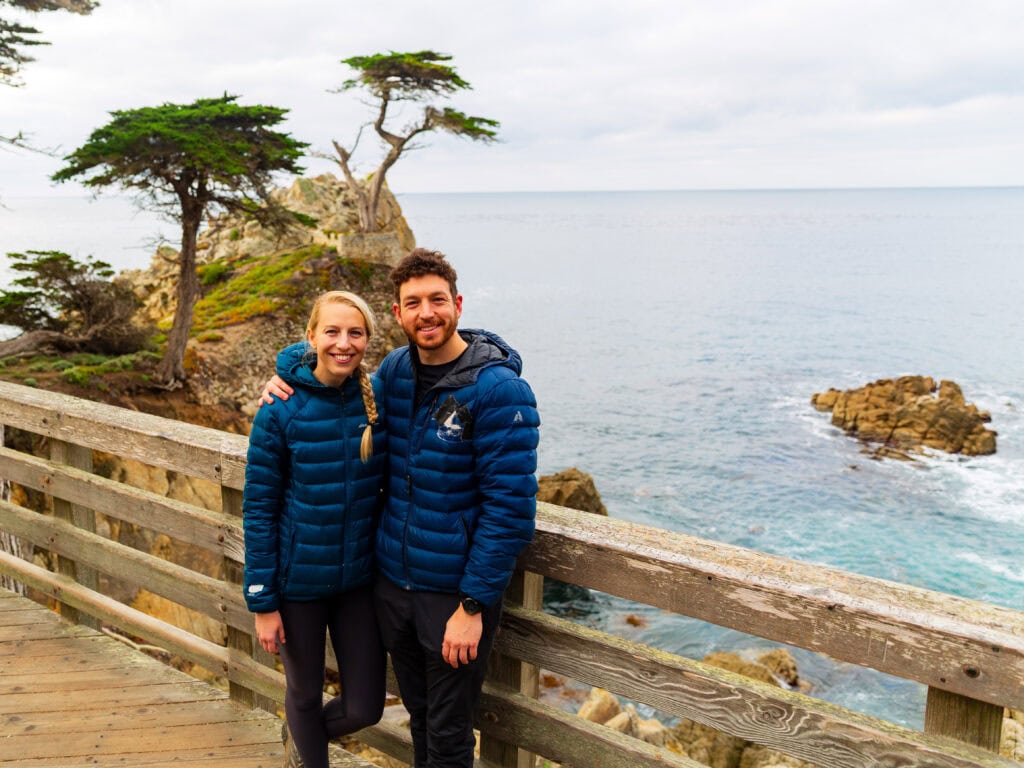 a man and woman look at the camera and smile on the 17-mile drive near pebble beach