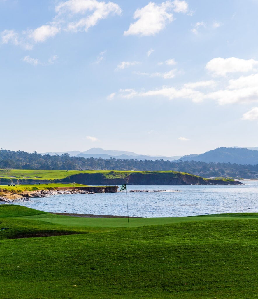 Expansive green fairways of Pebble Beach Golf Links with Stillwater Cove beyond