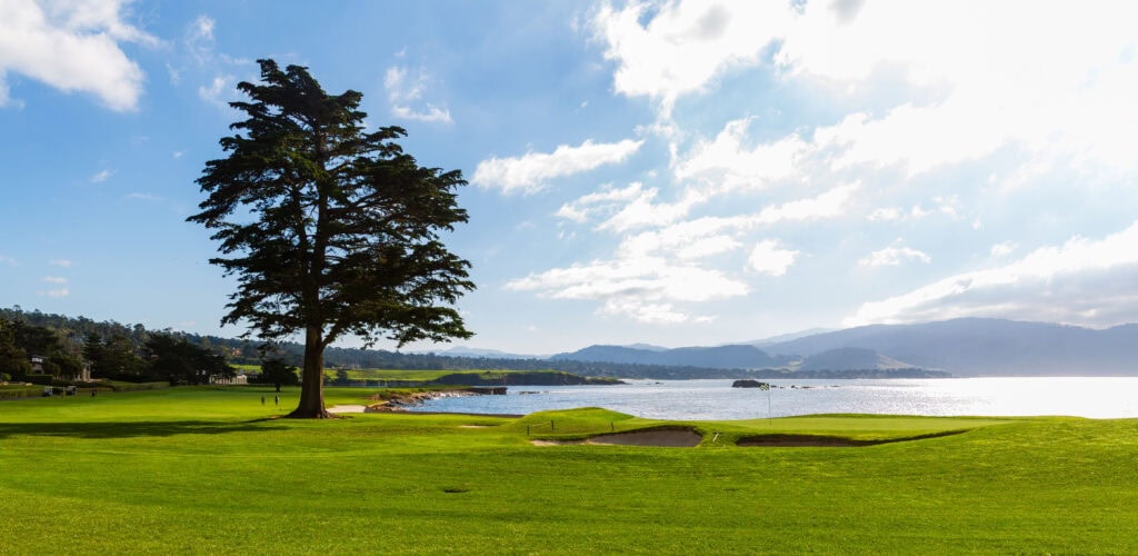 Expansive green fairways of Pebble Beach Golf Links with Stillwater Cove beyond