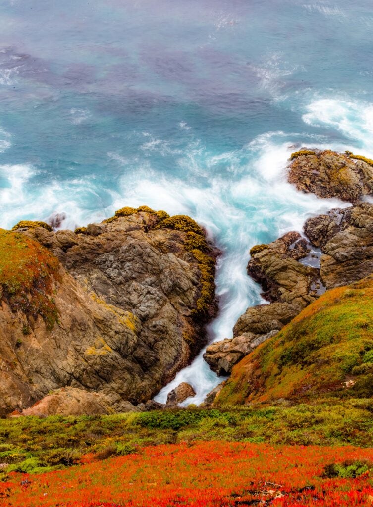 Rocky coastal cliffs with a natural arch and crashing surf in soft light