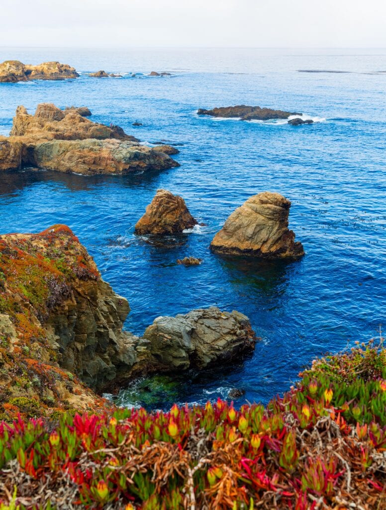 Sea stacks reflected in still water at a quiet coastal inlet