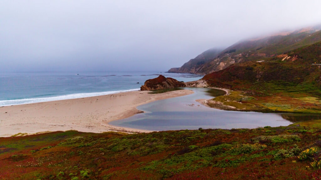 Sandy beach with layered rock formations under soft diffused light