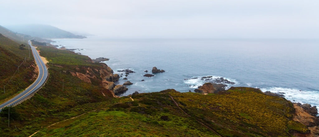 Foggy coastal headland with rocky outcroppings fading into marine layer