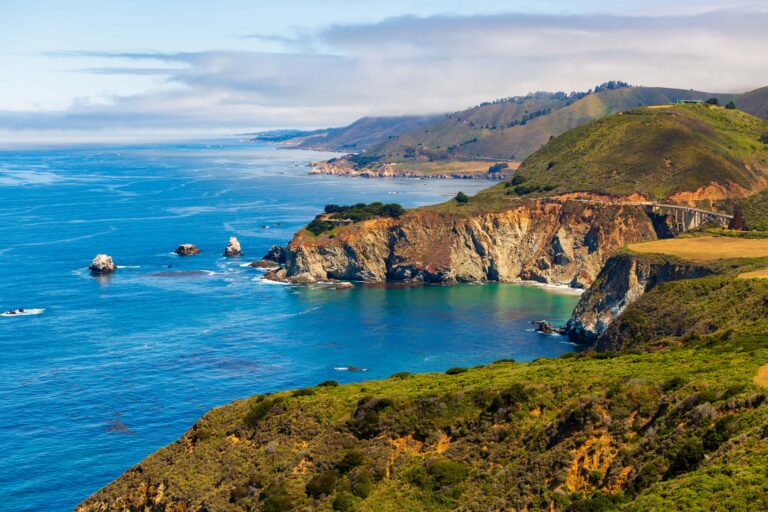Misty Big Sur coastline with rolling green hills meeting a gray-blue sea