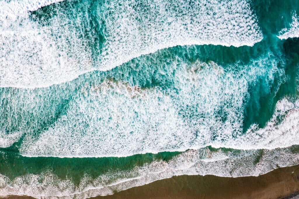 Overhead view of foamy white waves washing over a shallow reef