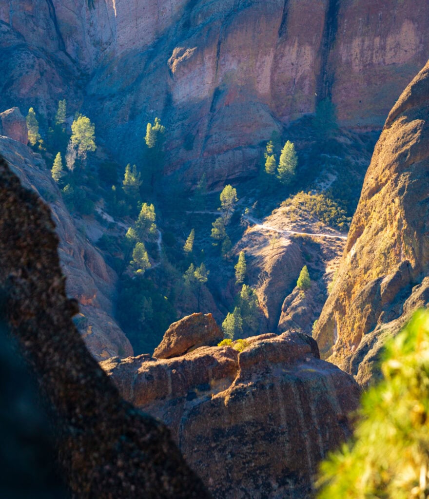 Looking down through a rocky cave opening into a deep red-orange canyon