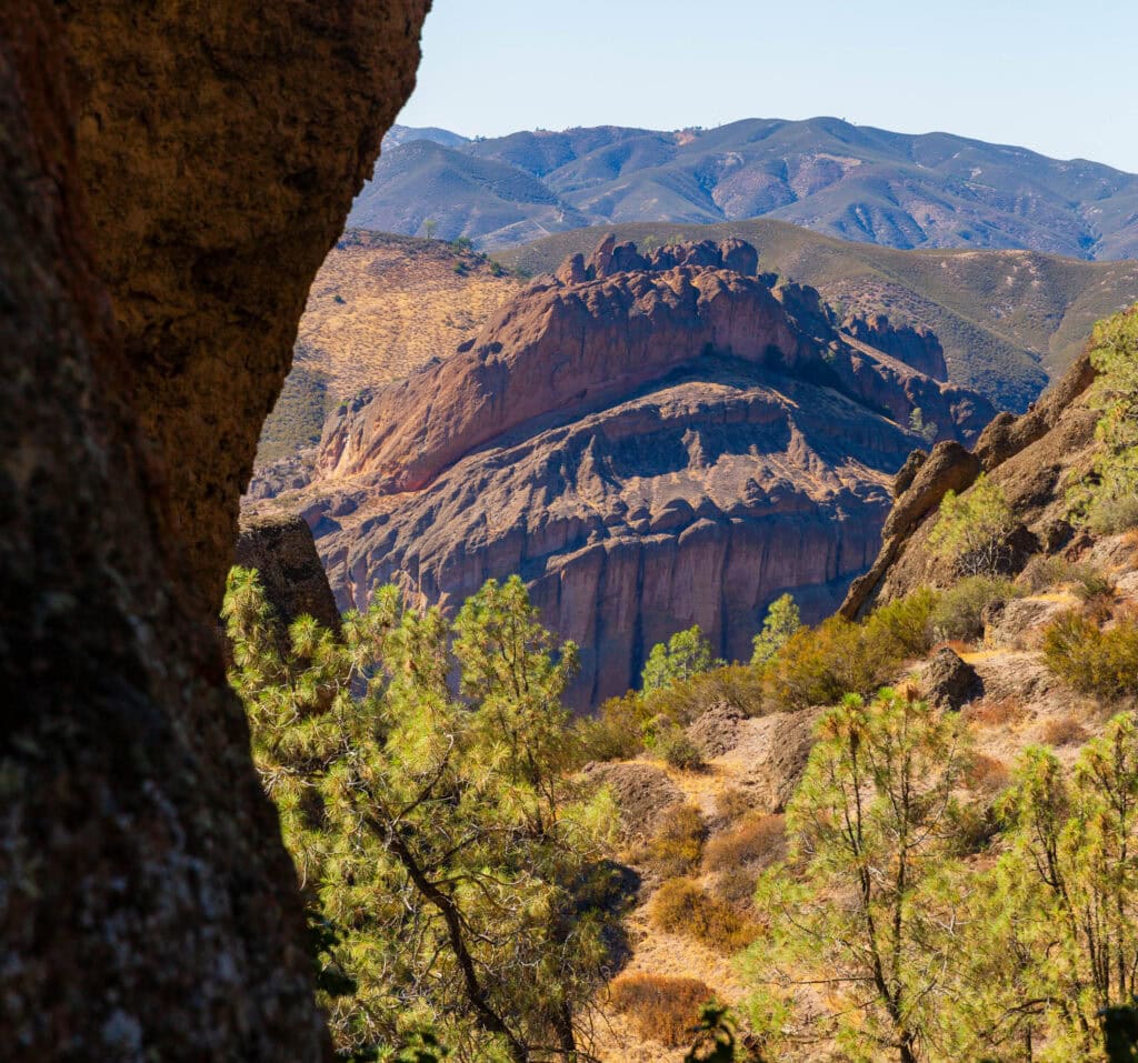 Looking down through a rocky cave opening into a deep red-orange canyon