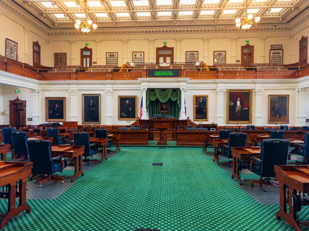 the inside of one of the chambers at the texas state capitol. there's green flooring