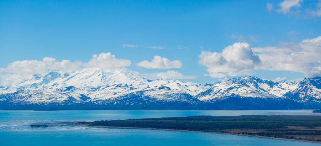 Snow-capped mountains reflected in a calm blue lake, Alaska